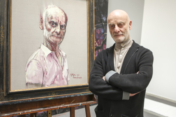 Swiss Art Collector Uli Sigg in  Zeng Fanzhi's home during the shooting of Michael Schindhelm's film about his life. Mr Sigg is standing in front of his portrait by artist Zeng Fanzhi. 
